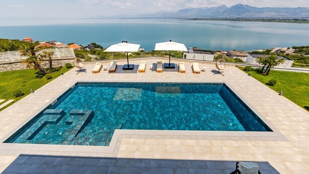 Une piscine rectangulaire à l’eau d’un bleu limpide, entourée d’une terrasse carrelée et de chaises longues.