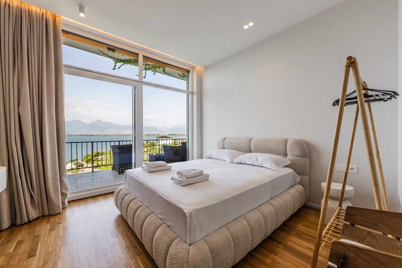 Une chambre avec un grand lit, une vue sur l’extérieur et un plancher en bois.