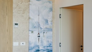 Ein Schlafzimmer mit einem Bett, Kissen, einem Wandbild und einer Tür.