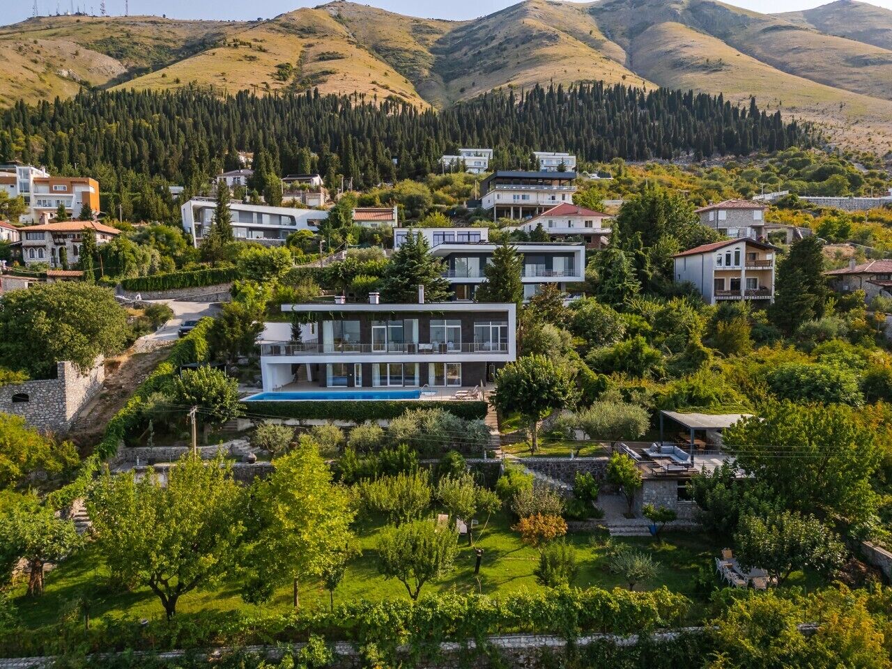 Un quartier résidentiel avec des maisons modernes, une piscine et un paysage verdoyant luxuriant.
