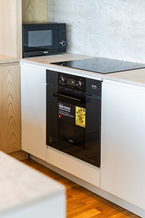 A modern kitchen with a built-in oven, microwave, and a display of the Van Gogh Museum Edition. - Sunset | The Twin Villa by PikHost (Shiroka)
