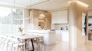 A modern kitchen with a central island, white cabinetry, and a dining area with a table and chairs.