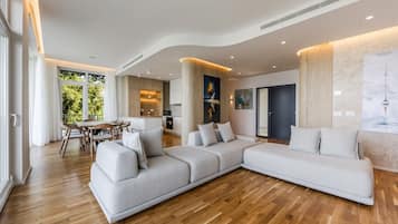 A modern living room with a large L-shaped sectional sofa, a dining area with a table and chairs, and a kitchen in the background.