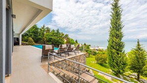 A modern outdoor patio with a stone staircase, a pool, and a view of the sea.
