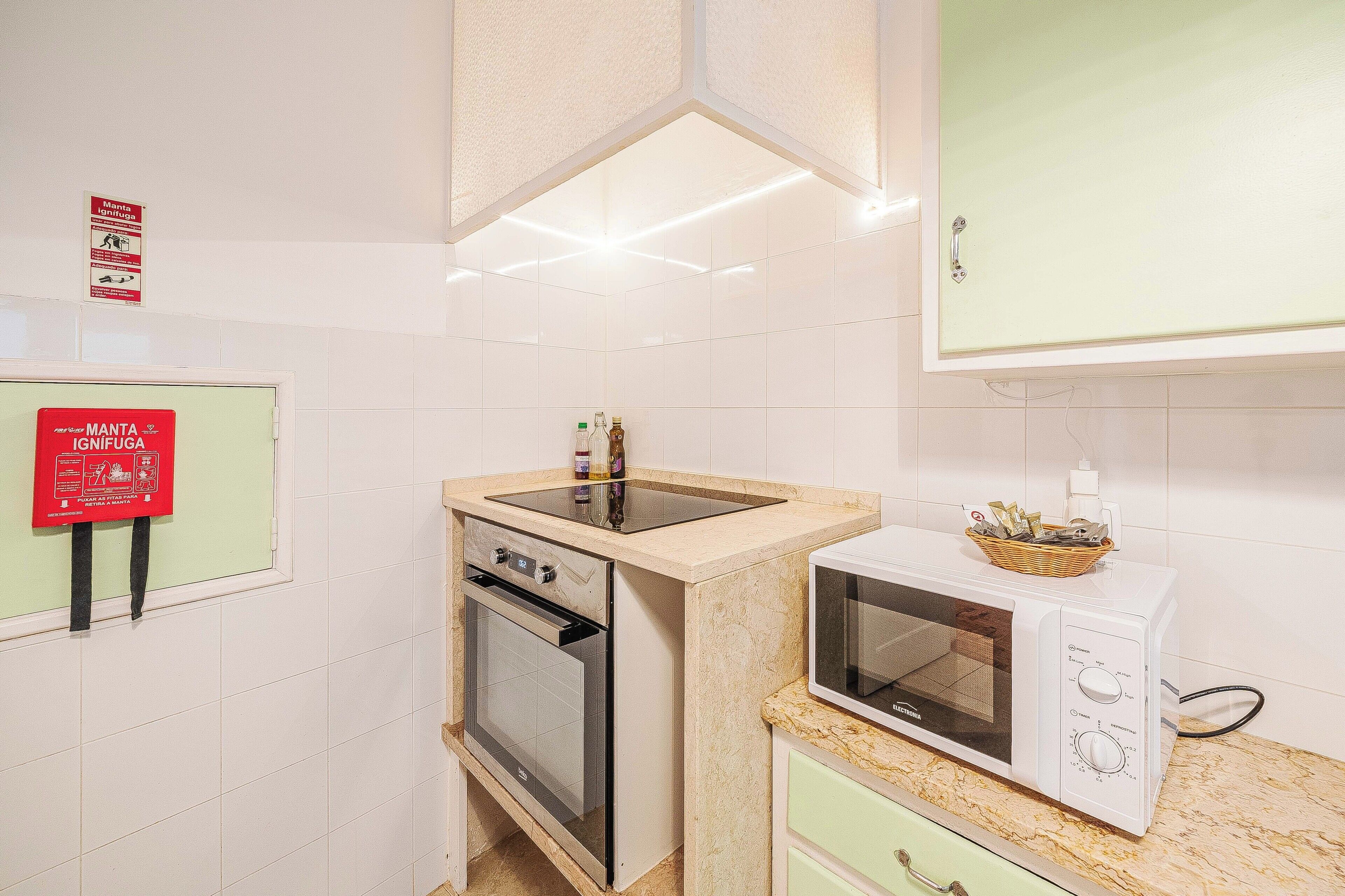 A kitchen with a microwave, oven, and a small sink.