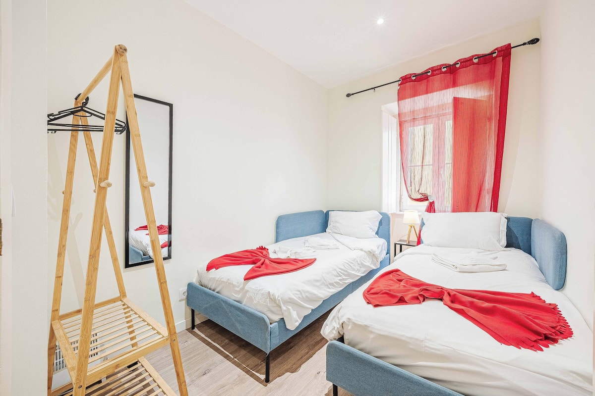 Ein Zimmer mit zwei Betten, einer Holzleiter und einem Spiegel an der Wand.