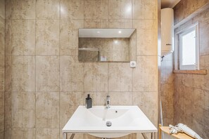 A bathroom with a white sink, a mirror, and a towel rack. - Quartos - Casas da Biquinha (Sintra)