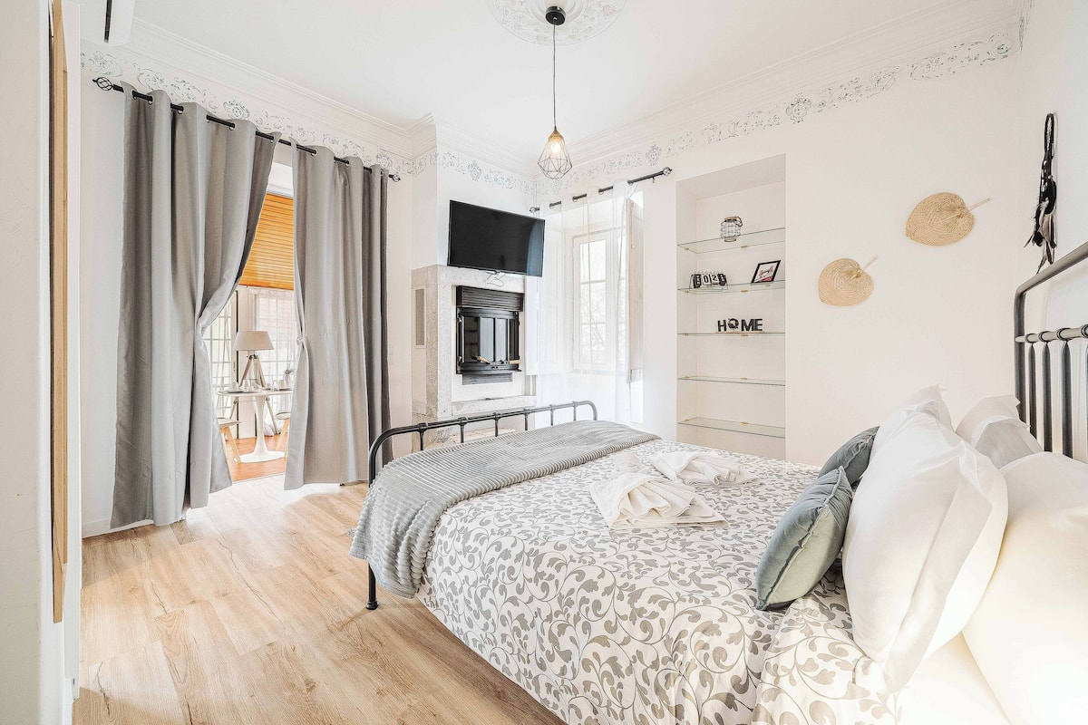 Ein Schlafzimmer mit Bett, Vorhängen, einem Fernseher und einem Regal mit Dekoration.