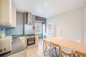 A modern kitchen with a built-in oven, a microwave, and a washing machine. - Quartos - Casas da Biquinha (Sintra)