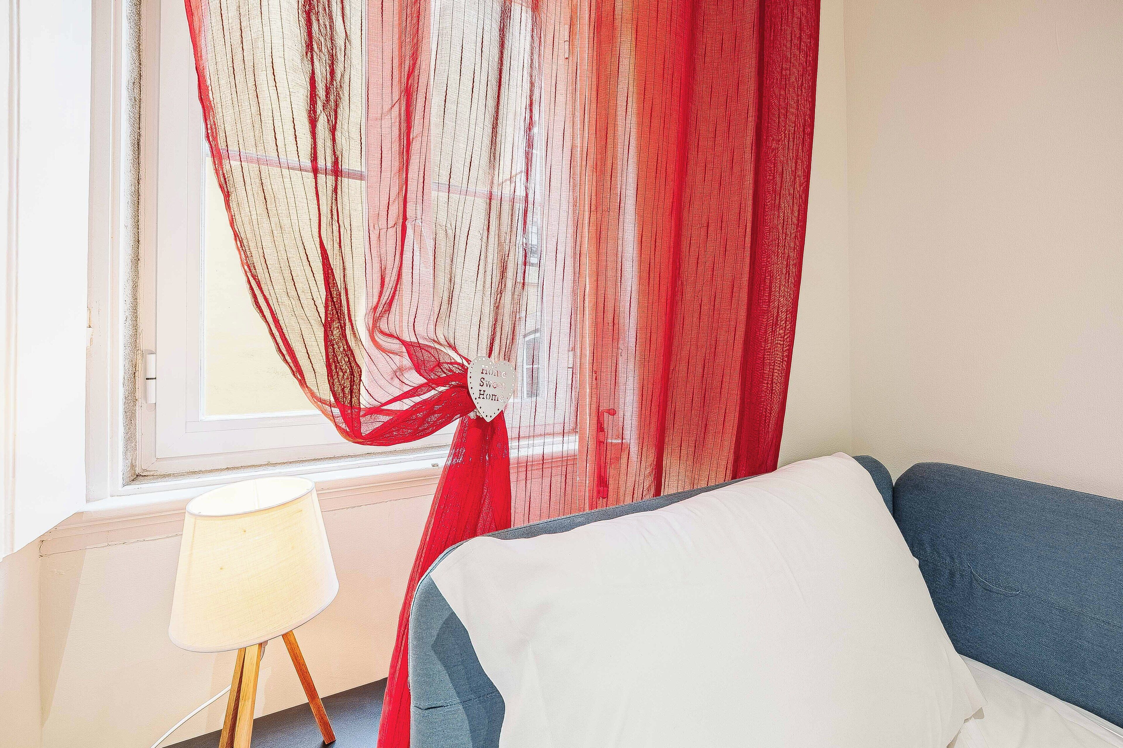 Een kamer met een bed, een lamp en een raam met dunne gordijnen.