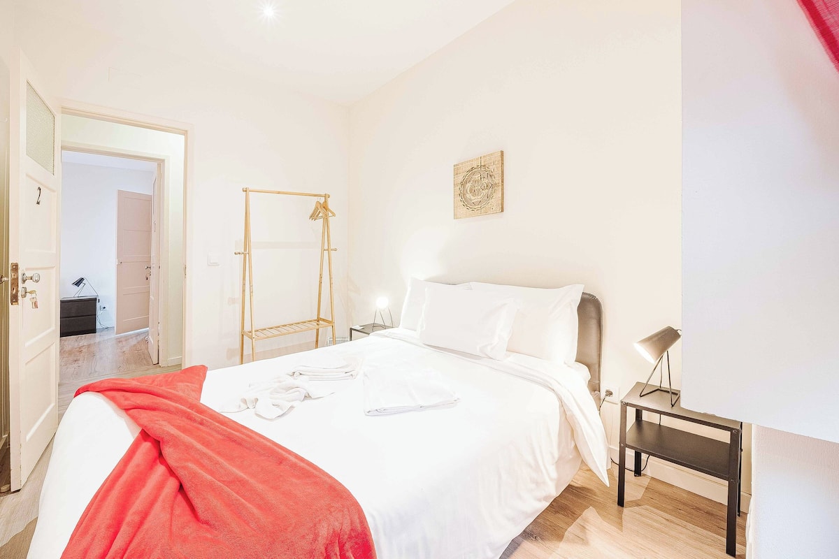 Ein Hotelzimmer mit Bett, Nachttisch, rotem Handtuch und Wandbild.