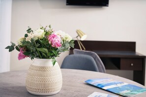 A vase with flowers on a table, a lamp, and a magazine.