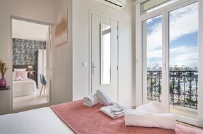 A hotel room with a bed, a red bath mat, and a balcony with a view of a Ferris wheel.