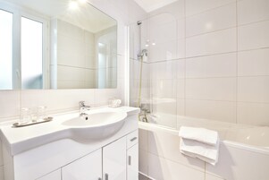 Un baño moderno con un espejo grande, dos lavamanos, ducha y bañera.