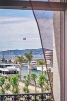 Vista de un puerto deportivo con barcos, un puente y un paisaje montañoso al fondo.