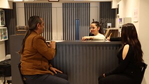 Een receptiegedeelte met een balie, stoelen en een bord aan de muur.