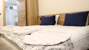 Een hotelkamer met een houten kledingkast, een bed met wit- en blauwe beddengoed en een geborduurde plaid.