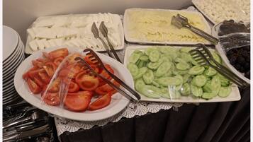 Ein Buffet mit verschiedenen Speisen, darunter Tomatenscheiben, Gurken, Käse und Trauben.