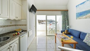 A kitchen with white cabinets, a granite countertop, and a dining area with a blue sofa and a table. - Vistaflor Puerto Plata (Mogan)