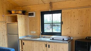 Une cuisine compacte avec des meubles en bois, un réfrigérateur encastré, une fenêtre offrant une belle vue et un poêle à bois.