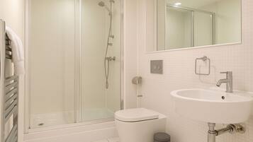 A modern bathroom with a glass-enclosed shower, a white sink, and a mirror above the sink.