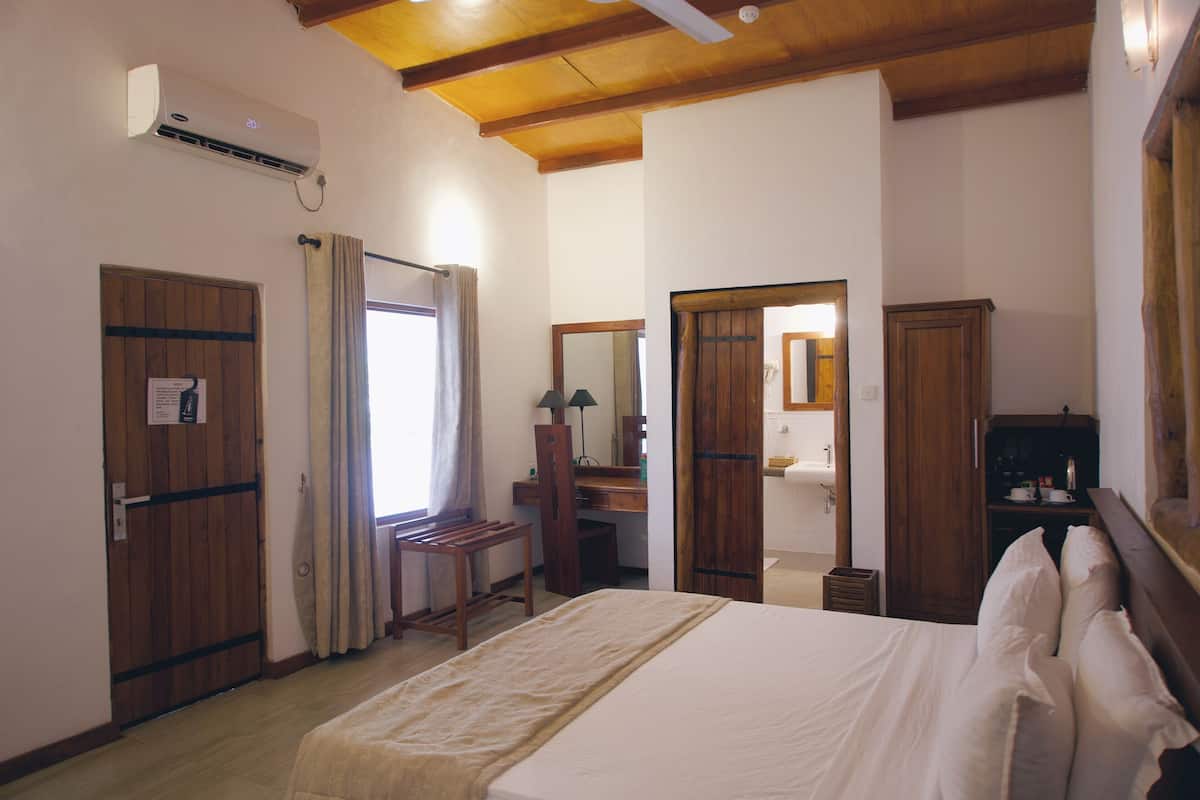 A bedroom with a bed, wooden wardrobe, desk, and a mirror.