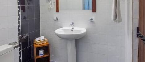 A bathroom with a white sink, a toilet, a mirror, and a towel rack.