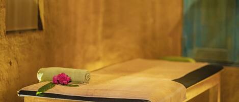Een houten massagetafel met een handdoek en een bloem.