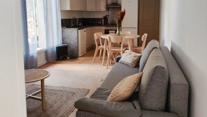 Una sala de estar moderna con un sofá gris, una mesita redonda y un comedor con sillas.