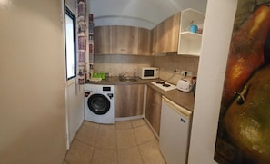 Compact kitchen with washer and dryer, microwave, and sink, perfect for food preparation.