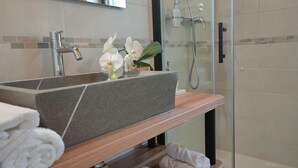 A bathroom with a granite sink, a wooden shelf with towels, and a glass shower enclosure. - Le Acacie (Torreano)