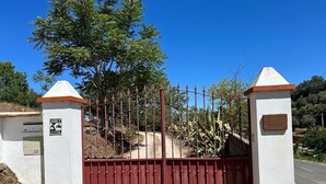 A gated entrance with a metal fence and two white pillars with orange tops. - Amazing view to the Castle! Beautiful renewed country house. 5m walk to village. (Castelo de Vide)