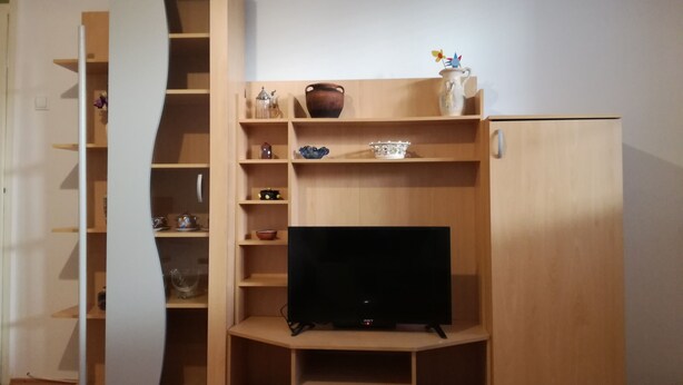 Een knus woongedeelte met een ingebouwde televisie, houten planken en een klein kastje.
