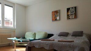 Een slaapkamer met een bed, een tafel en twee schilderijen aan de muur.