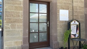 A stone building with a brown door, a sign reading "HOTEL," and a small table with a plant. - Hotel am Bahnhof Ditzingen (Ditzingen)