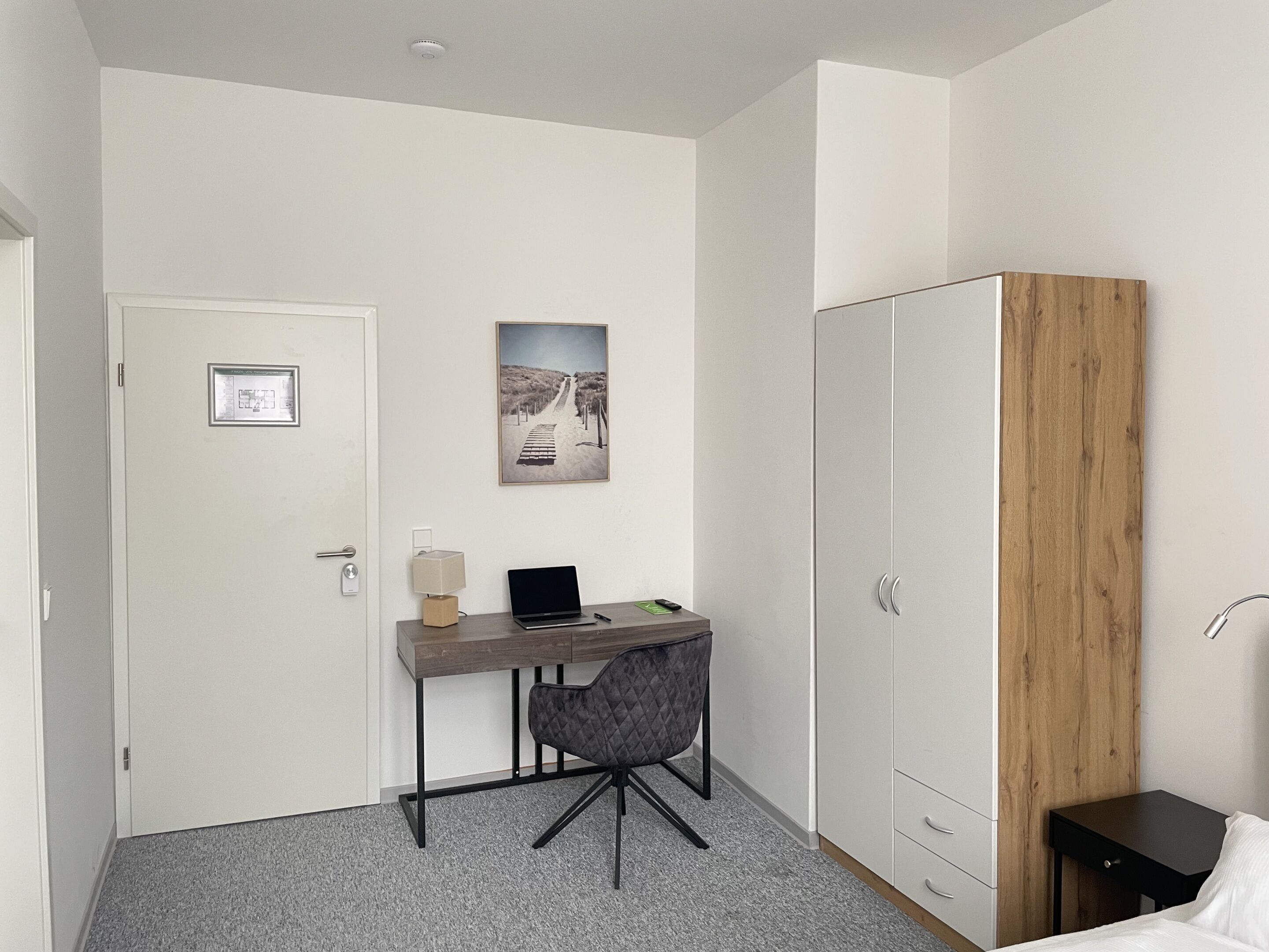 A small, modern room with a desk, chair, and wardrobe.