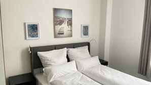 A neatly made bed with white linens in a hotel room. - Hotel am Bahnhof Ditzingen (Ditzingen)