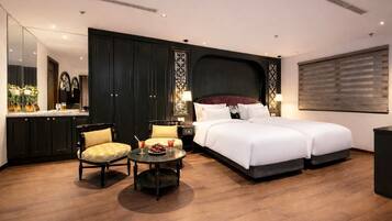 A hotel room with a large bed, a desk with a chair, a small table with a drink, and a large mirror.