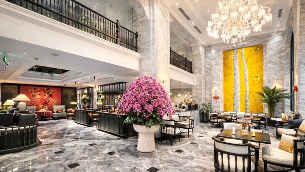 Eine großzügige Lobby mit Marmorböden, einem großen Kronleuchter und einer zentralen Blumenkomposition.