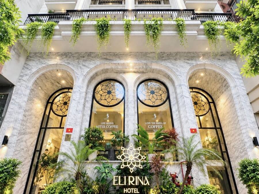 Het uiterlijk van het Elrina Hotel, met een marmeren gevel, gebogen ramen en beplanting op de balkons.