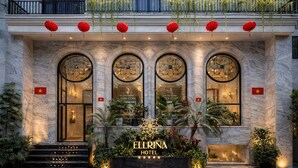 Ein Hotel Eingang mit drei Rundbogenfenstern, einem Schild mit der Aufschrift 'ELLRINA HOTEL' und einer Flagge auf jeder Seite.
