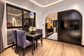 Una zona menjador moderna amb una taula de fusta fosca, cadires tapissades de color morat i un ram de flors.