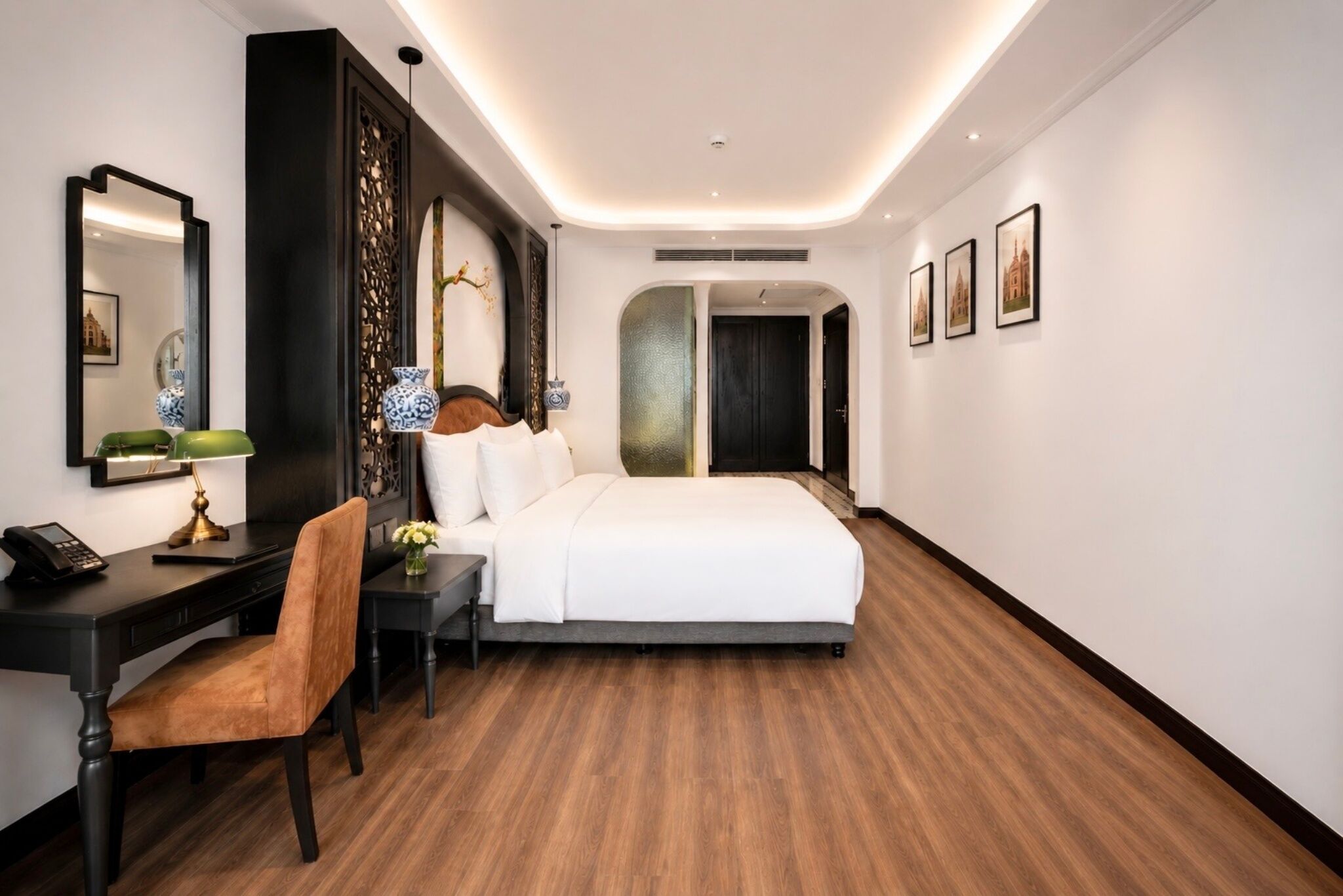 A hotel room with a bed, desk, chair, and a mirror.