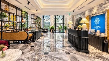 Eine Hotelhalle mit Marmorboden, einer Rezeption, einer Sitzecke und einer Treppe.