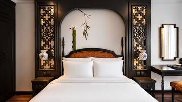 Een hotelkamer met een groot bed, een houten hoofdbord, decoratieve wandpanelen en een nachtkastje met een lamp.