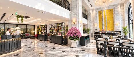 A hotel lobby with a reception desk, seating area, and a chandelier.