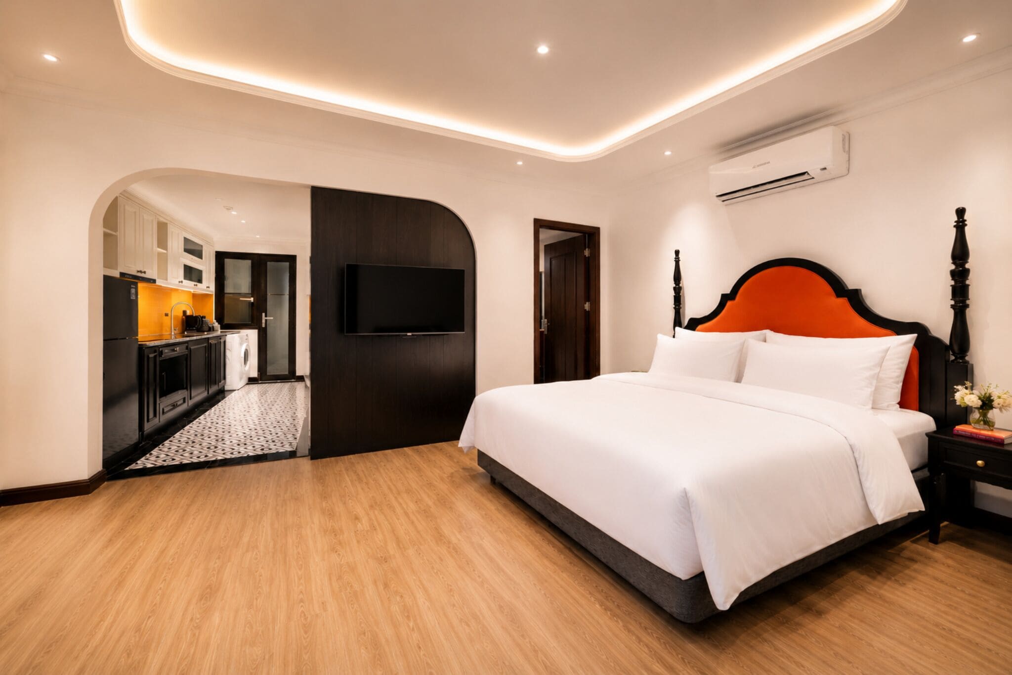 Une chambre d’hôtel équipée d’un lit, d’une télévision, d’un climatiseur et offrant une vue sur la cuisine.