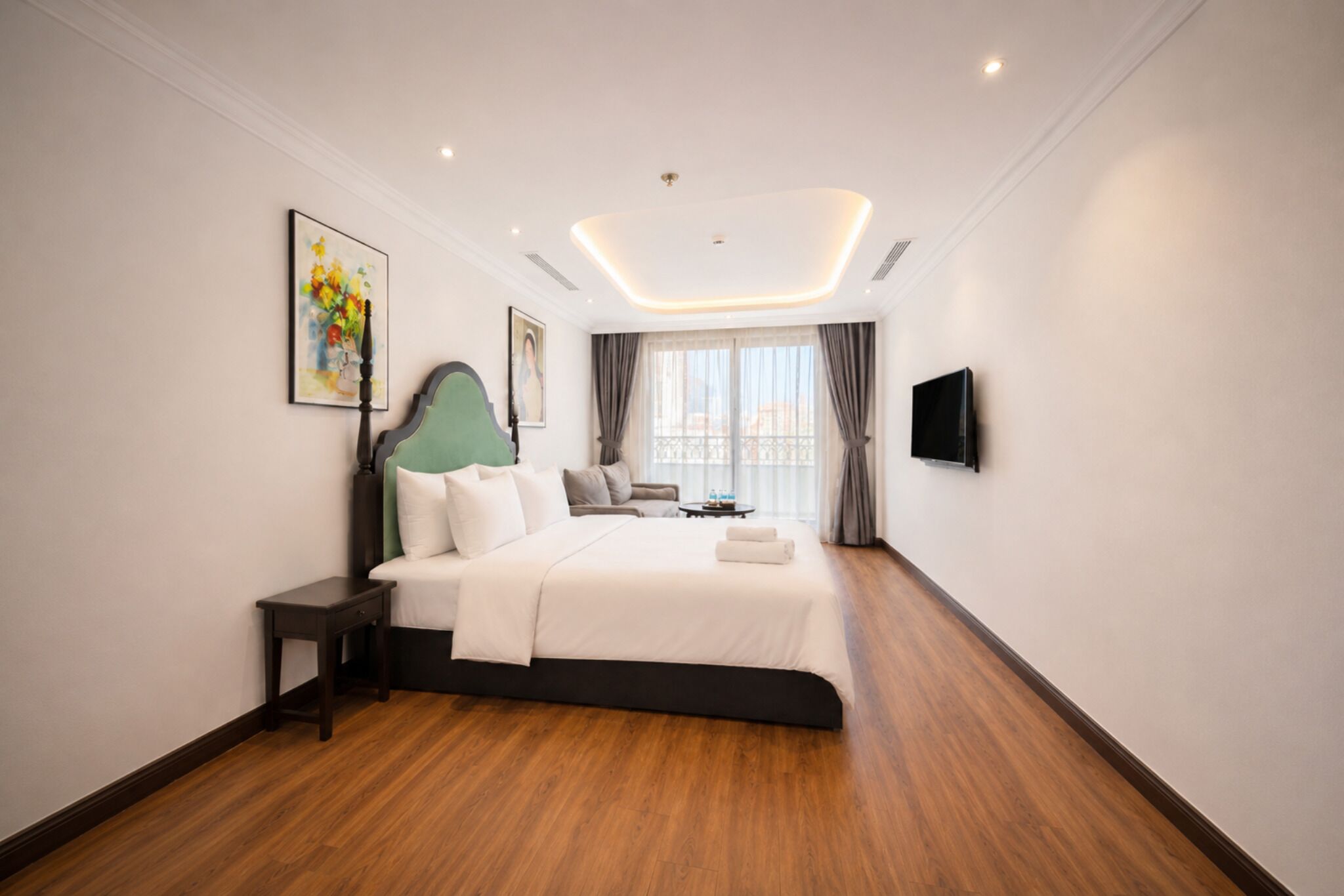 A modern hotel room with a large bed, a flat-screen TV, and a painting on the wall.