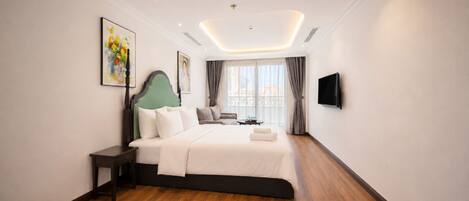 A modern hotel room with a large bed, a flat-screen TV, and a painting on the wall.