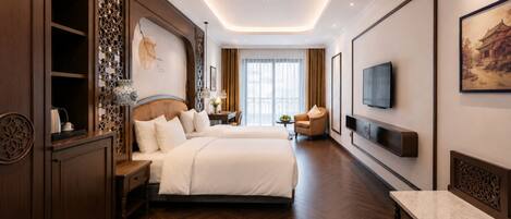 A hotel room with a large bed, a TV mounted on the wall, a wooden cabinet, and a decorative screen.